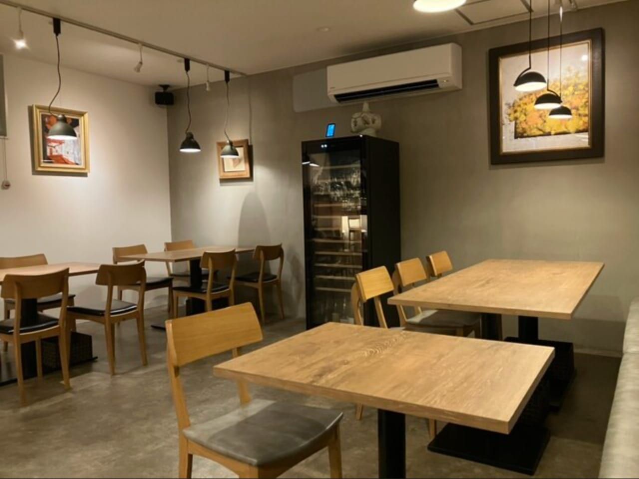 木のテーブルが並ぶ客席。奥にワインセラー