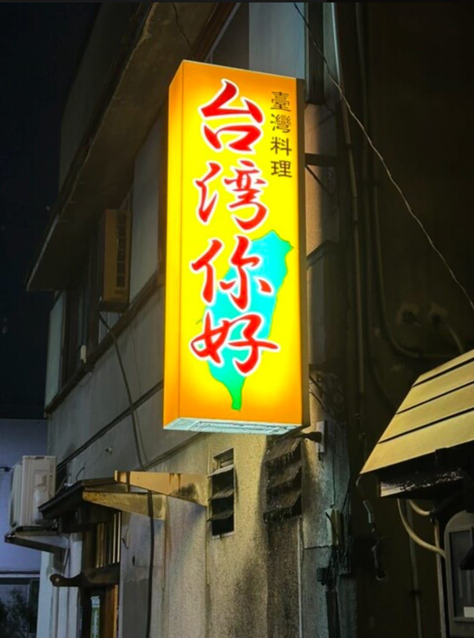夜裡亮起的「臺灣料理 台湾你好」黃色霓虹招牌