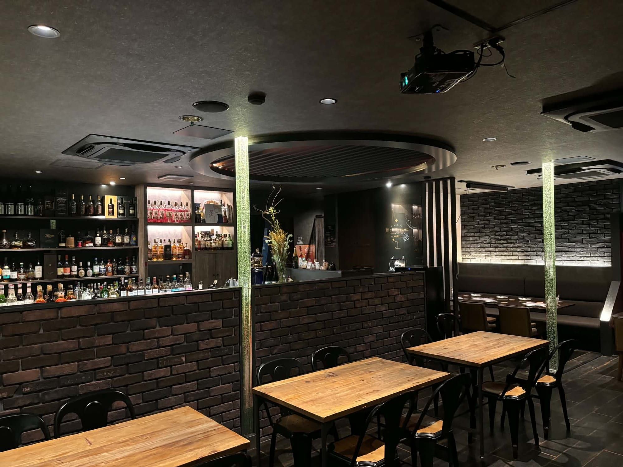 Dining lounge with brick walls, and a bar counter with bottle shelves at the back